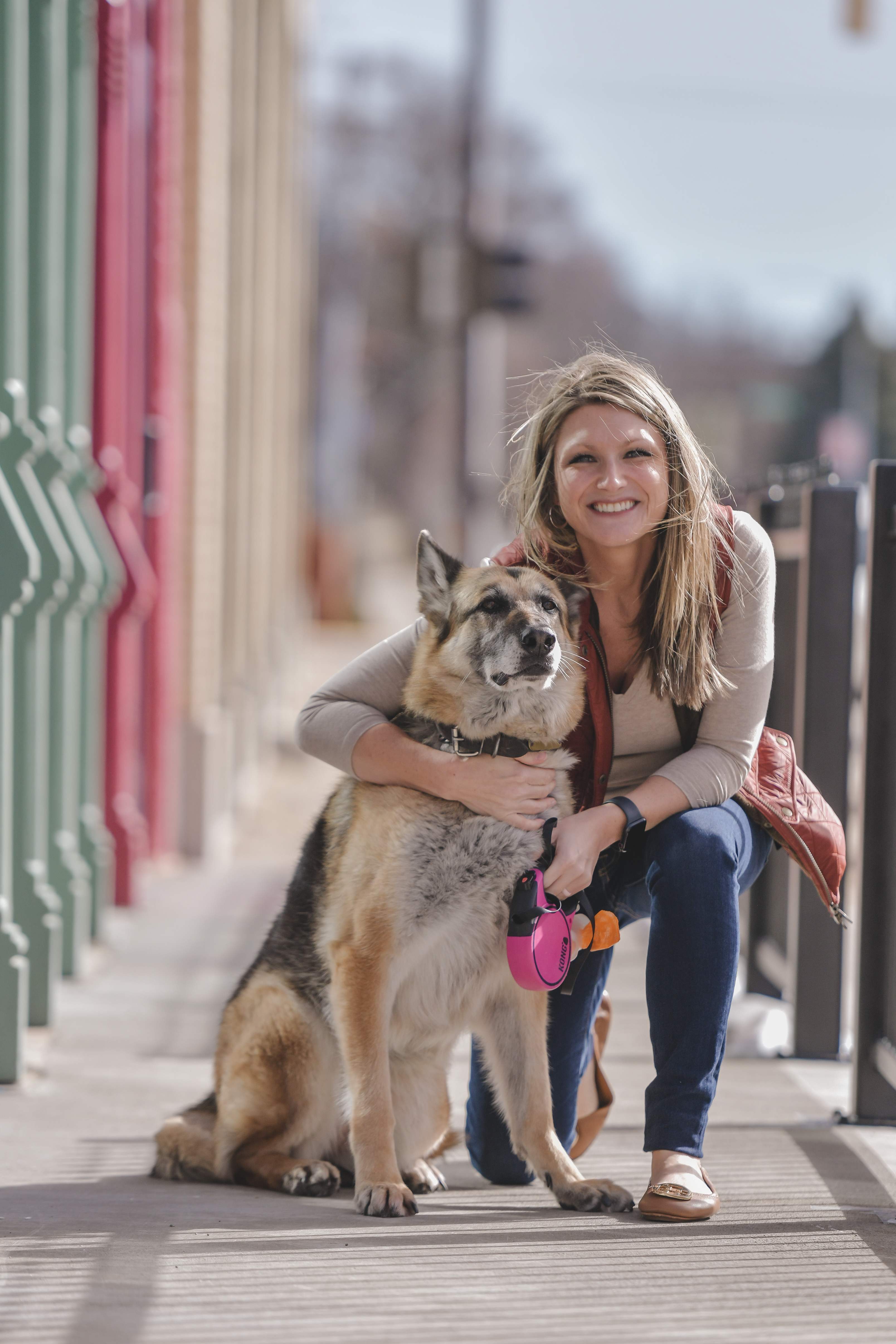 Happy owner hugging her big dog on a city sidewalk
